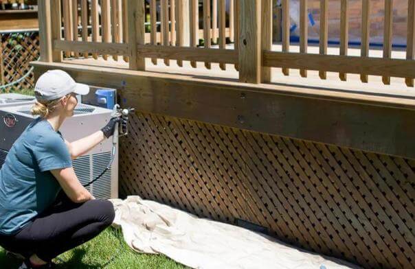 girl using airless sprayer for deck staining