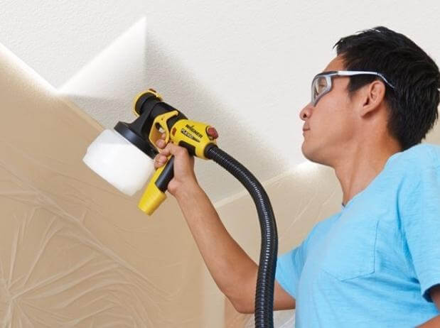 man using wagner indoor paint sprayer for interior walls